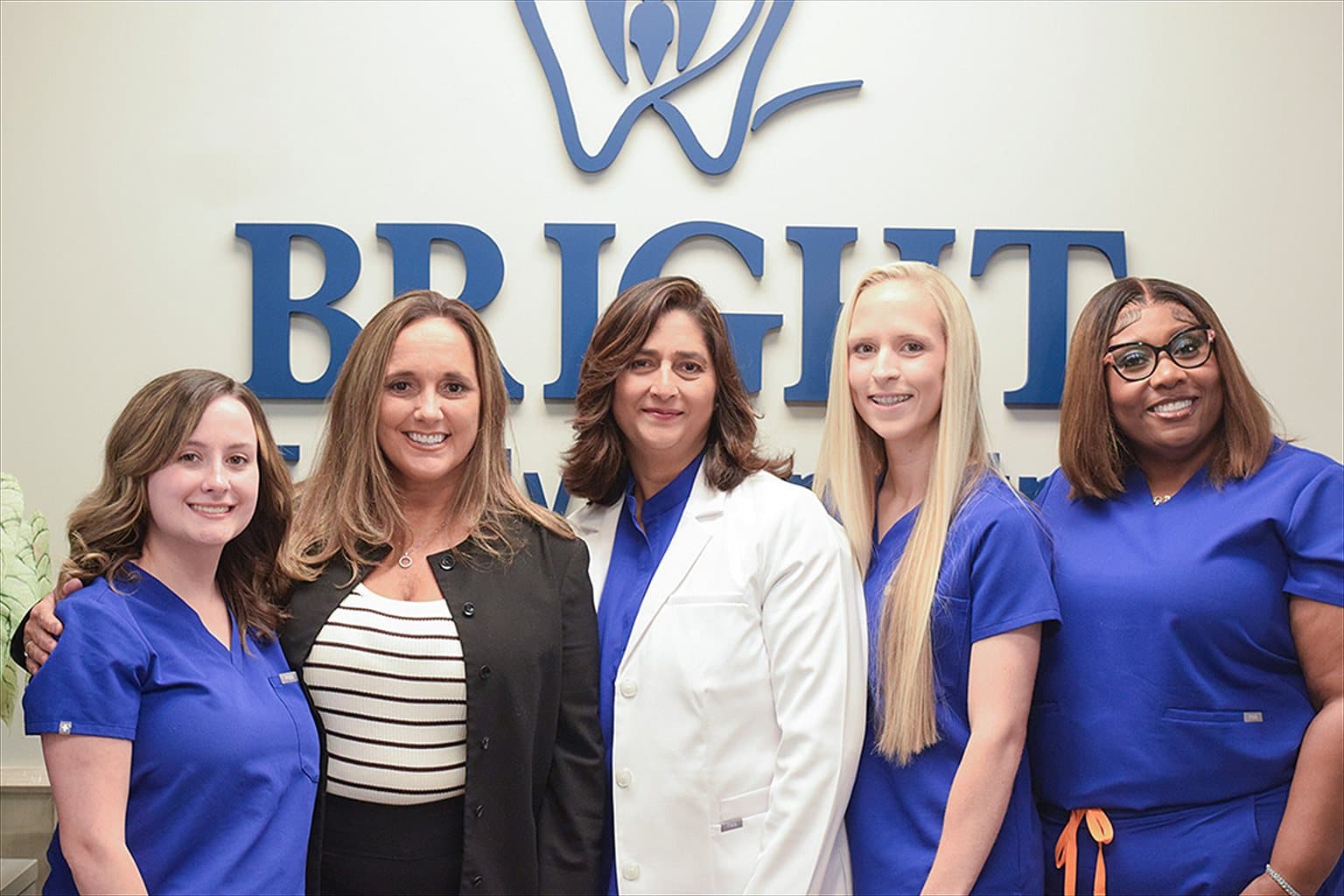 The Bright Family Dentistry team in front of the lobby sign